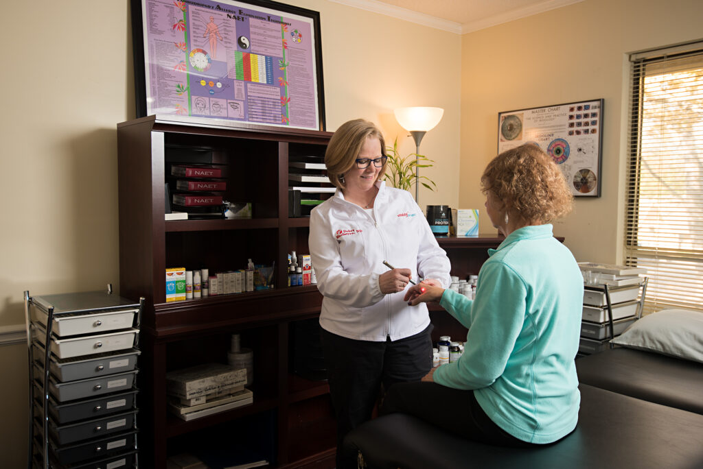 Debra MacIntyre using laser on patient hand in clinic.
