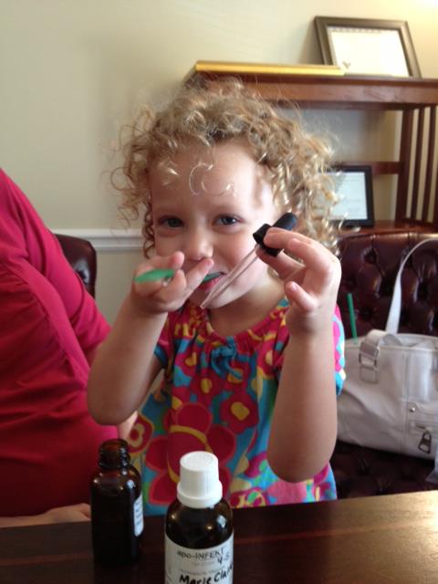 Child playing with droppers and bottles at table.