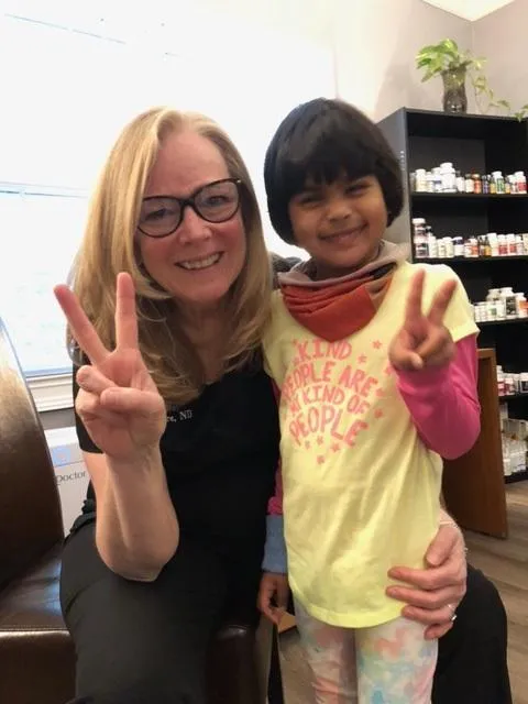 Debra MacIntyre together with a child smiling and posing with peace signs.