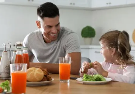 Father and daughter enjoying breakfast together at table.