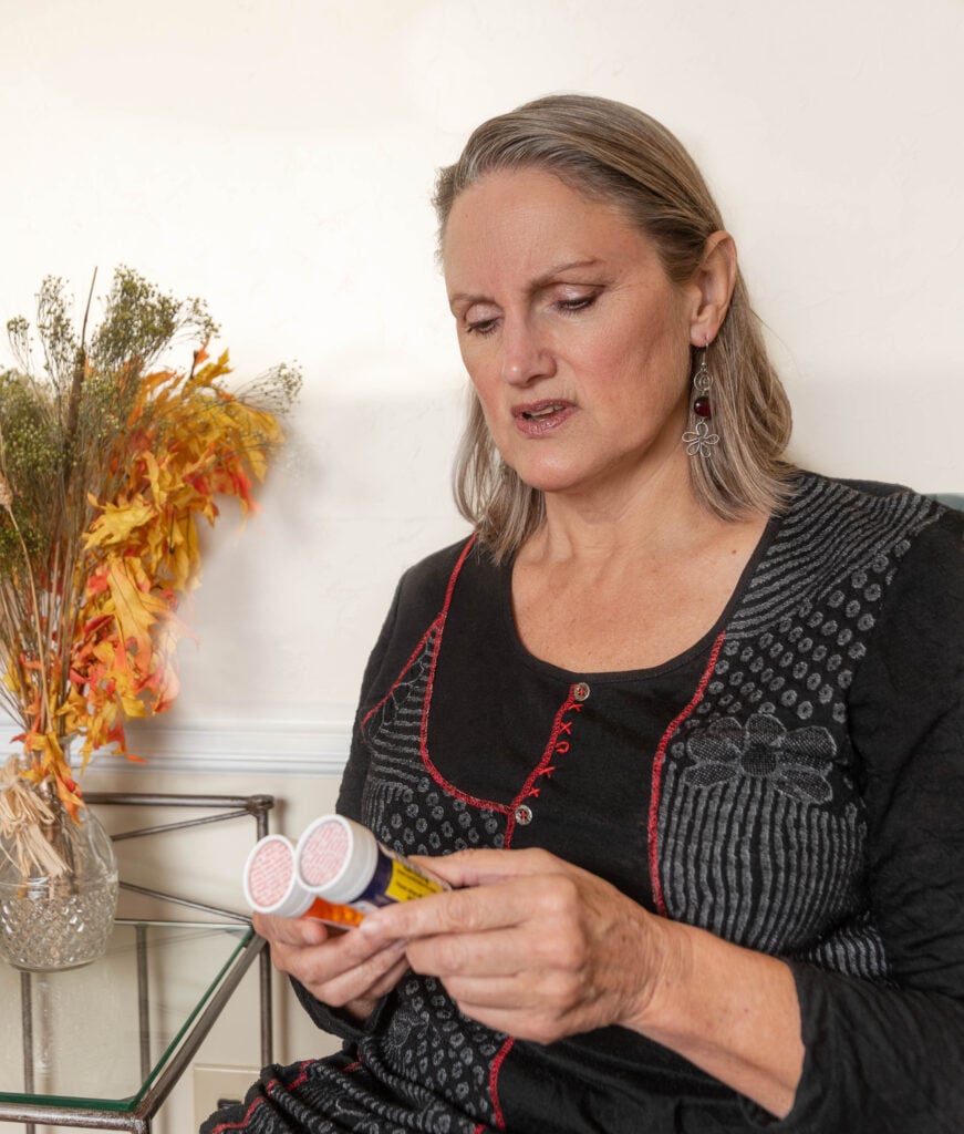 Woman reading medication bottles at home