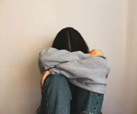 Person sitting with head down in a hoodie.